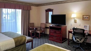 Een hotelkamer met twee bedden, een televisie, een bureau met stoel en een lamp.