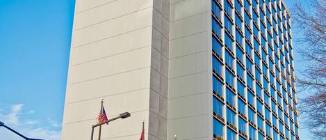 A Hilton hotel with a modern facade, a Starbucks, and a clear blue sky.