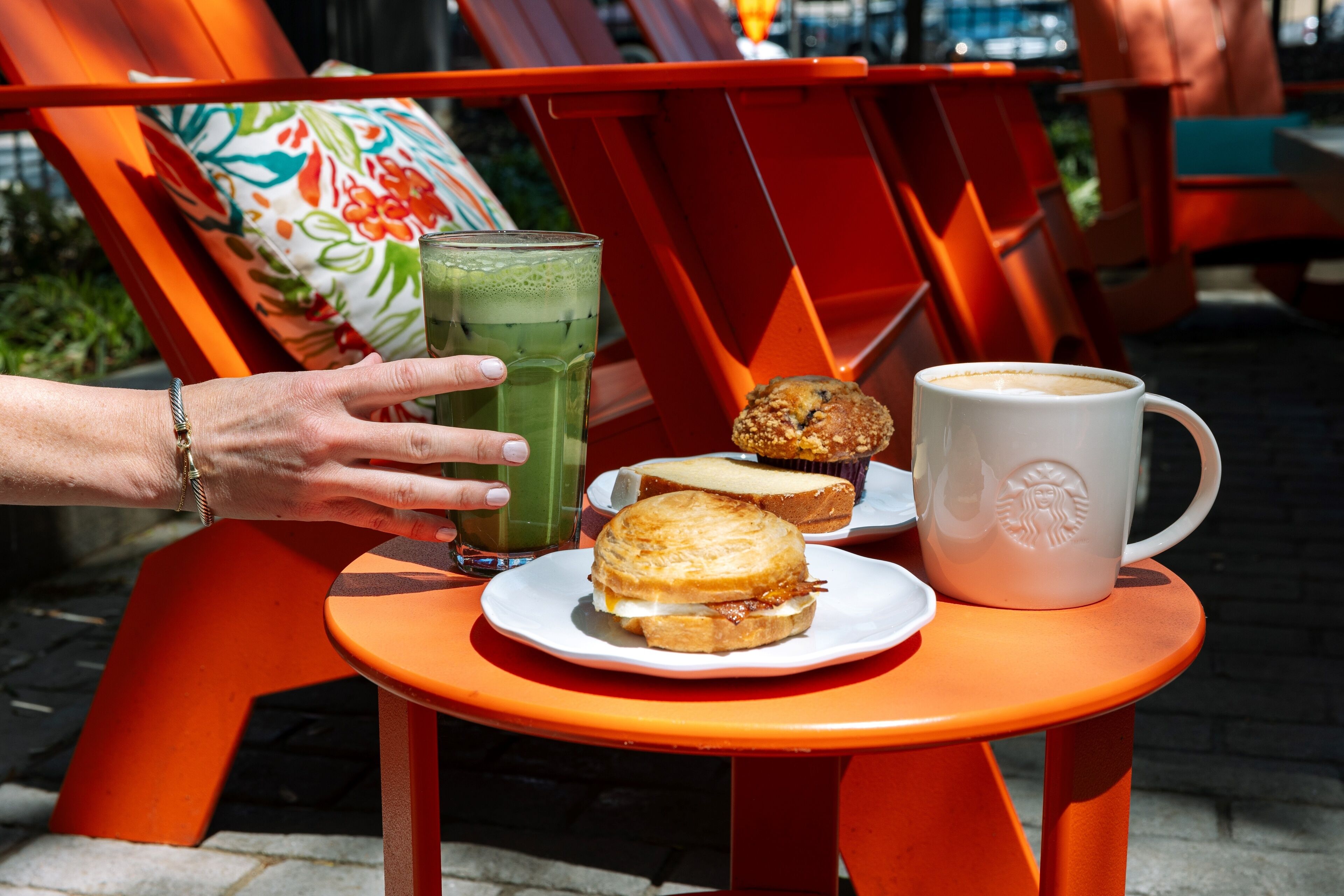 A table with a plate of food, a glass of green beverage, and a white mug.