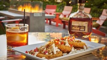A table with a plate of food, a drink, and a bottle of liquor.