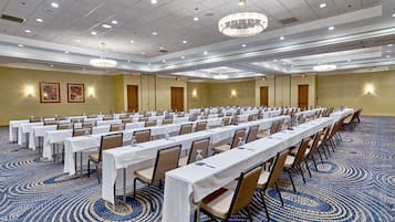 A large conference room with rows of tables and chairs, equipped with water bottles and nameplates.