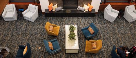 A lobby with a fireplace, multiple seating areas, and a television.