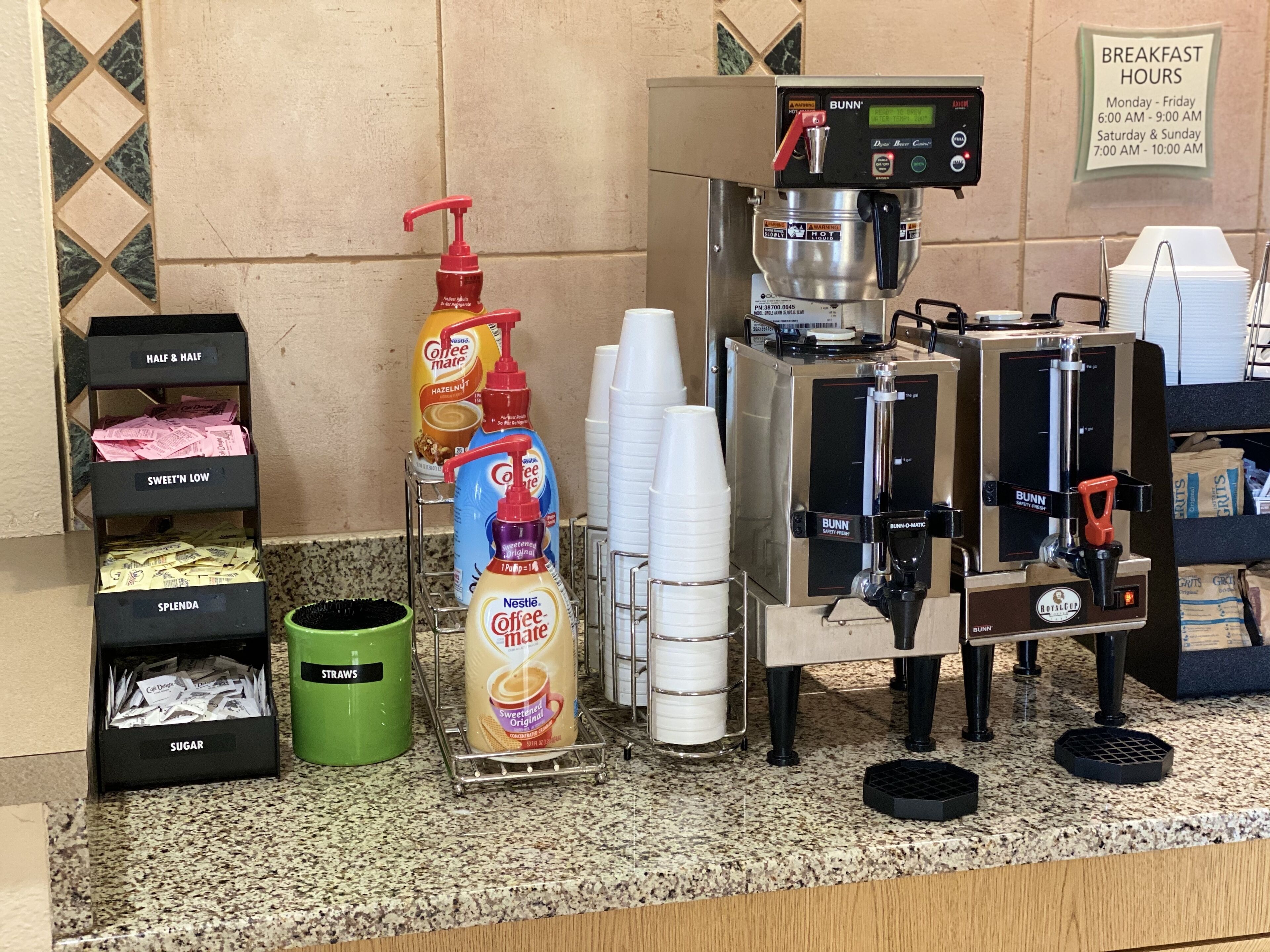 A coffee station with a coffee machine, cups, and various coffee creamer options.