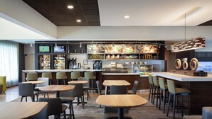 A modern restaurant with a bar area, multiple seating options, and a variety of food and drink displays. - Courtyard by Marriott Tampa Westshore/Airport (Tampa)