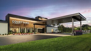 A Courtyard by Marriott hotel with a modern design, featuring a covered entrance and well-maintained landscaping. - Courtyard by Marriott Tampa Westshore/Airport (Tampa)
