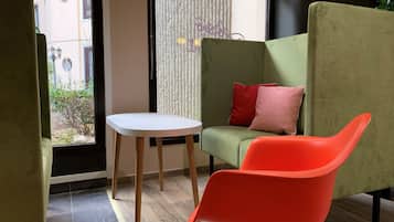 A modern room with a green sofa, a red chair, and a small white table.
