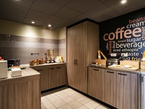 A modern kitchen with wooden cabinets, a coffee station, and a word cloud on the wall. - ibis Tours Centre Gare (Tours)