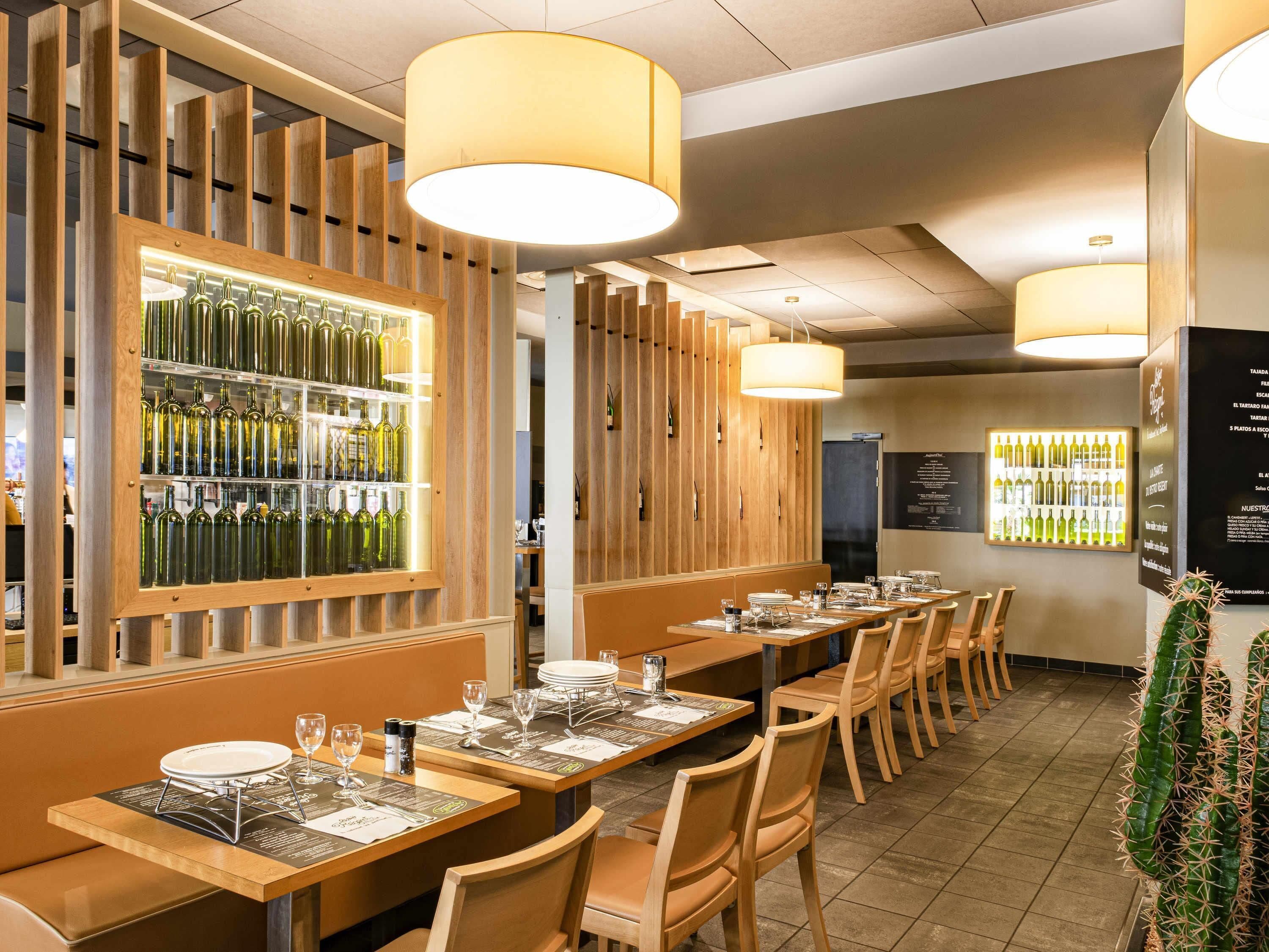 A restaurant interior with wooden paneling, tables set with plates and glasses, and a wine display.