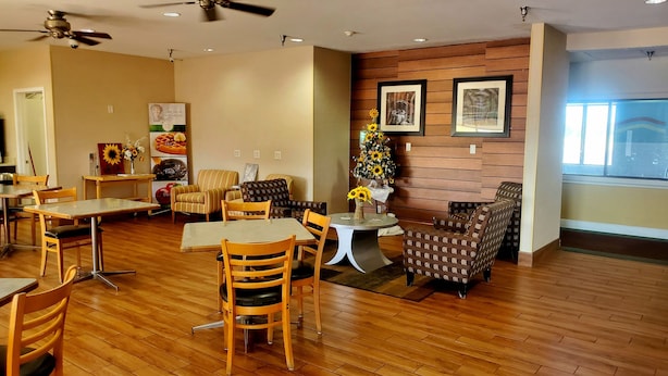 A dining area with wooden flooring, tables, and chairs. There are ceiling fans, a wall-mounted clock, and framed pictures. - Quality Inn Peru near Starved Rock State Park (La Salle)