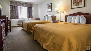 A hotel room with two beds, a desk, a chair, a lamp, and a window with curtains. - Quality Inn Peru near Starved Rock State Park (La Salle)