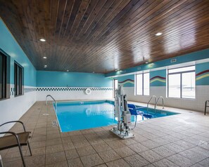 An indoor swimming pool with a wooden ceiling, tiled floor, and a lifeguard chair.