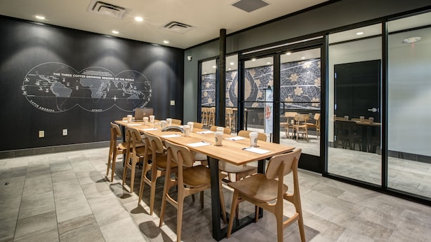 A conference room with a long table, chairs, and a world map on the wall.