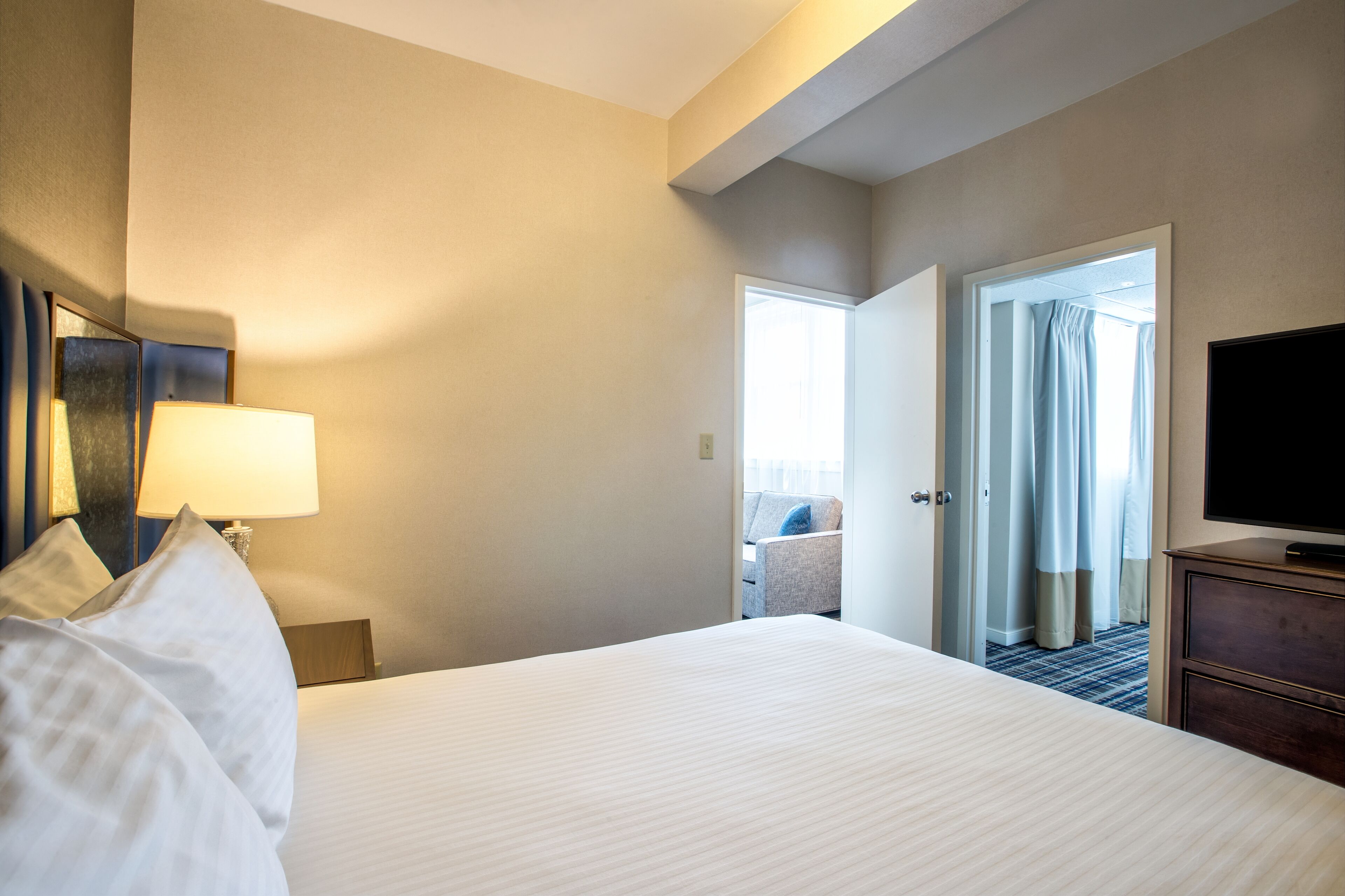 Ein Hotelzimmer mit einem großen Bett, einem Fernseher, einem Schreibtisch und einem Sessel.