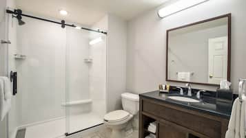 A modern bathroom with a glass-enclosed shower, a toilet, a sink with a mirror, and neatly arranged towels.