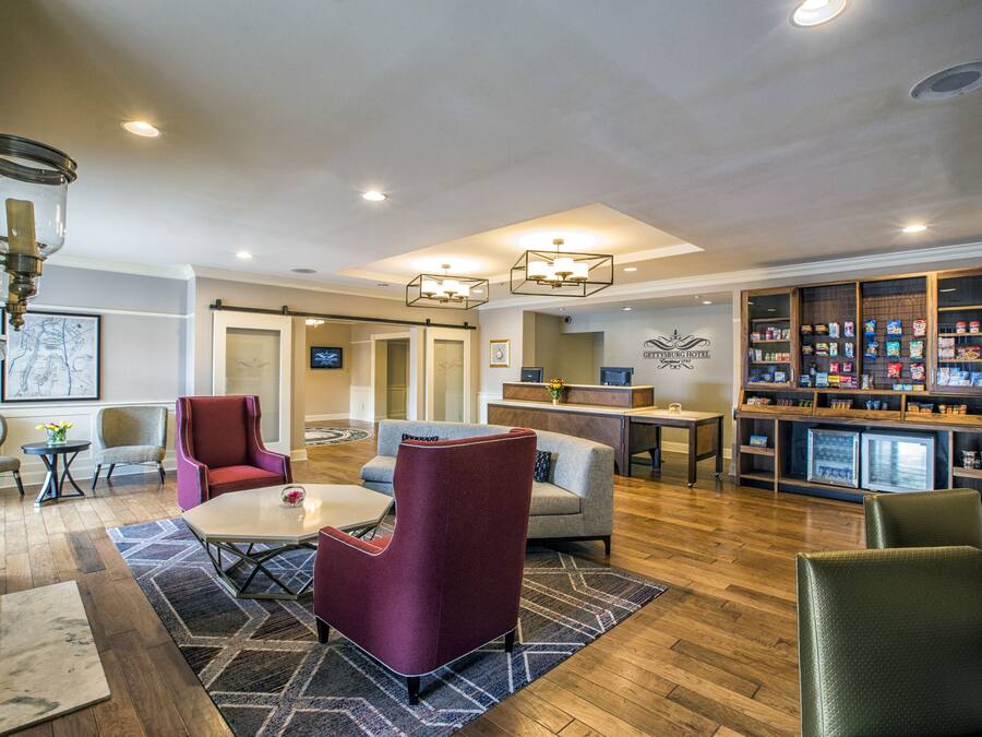 A hotel lobby with seating, a reception desk, a display case, and a television.