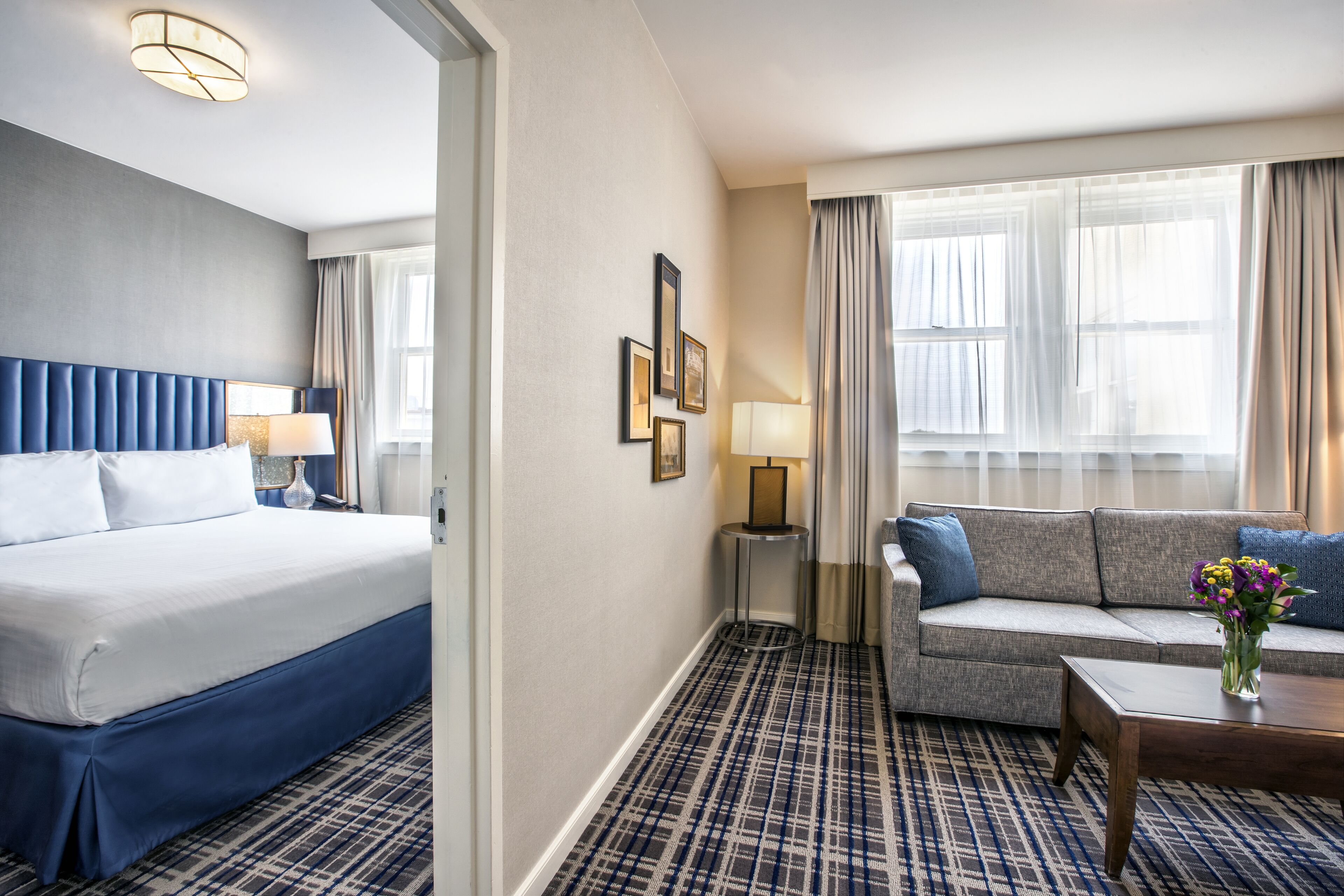 A hotel room with a bed, a sofa, a coffee table, and a lamp.