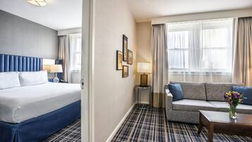 A hotel room with a bed, a sofa, a coffee table, and a lamp.