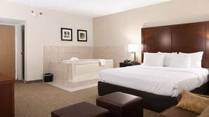 A hotel room with a large bed, a separate bathroom with a bathtub, a desk, and a chair. - Comfort Inn  Farmington Hills - Detroit Northwest (Farmington Hills)