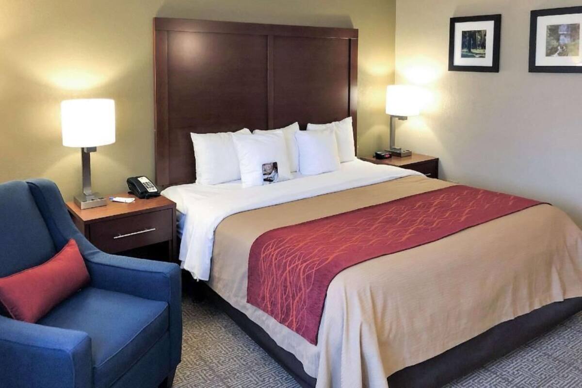 A hotel room with a bed, two bedside tables, a chair, and two wall-mounted lamps.