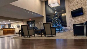 A lobby with a reception desk, a Christmas tree, and a seating area with chairs and a table. - Comfort Inn  Farmington Hills - Detroit Northwest (Farmington Hills)