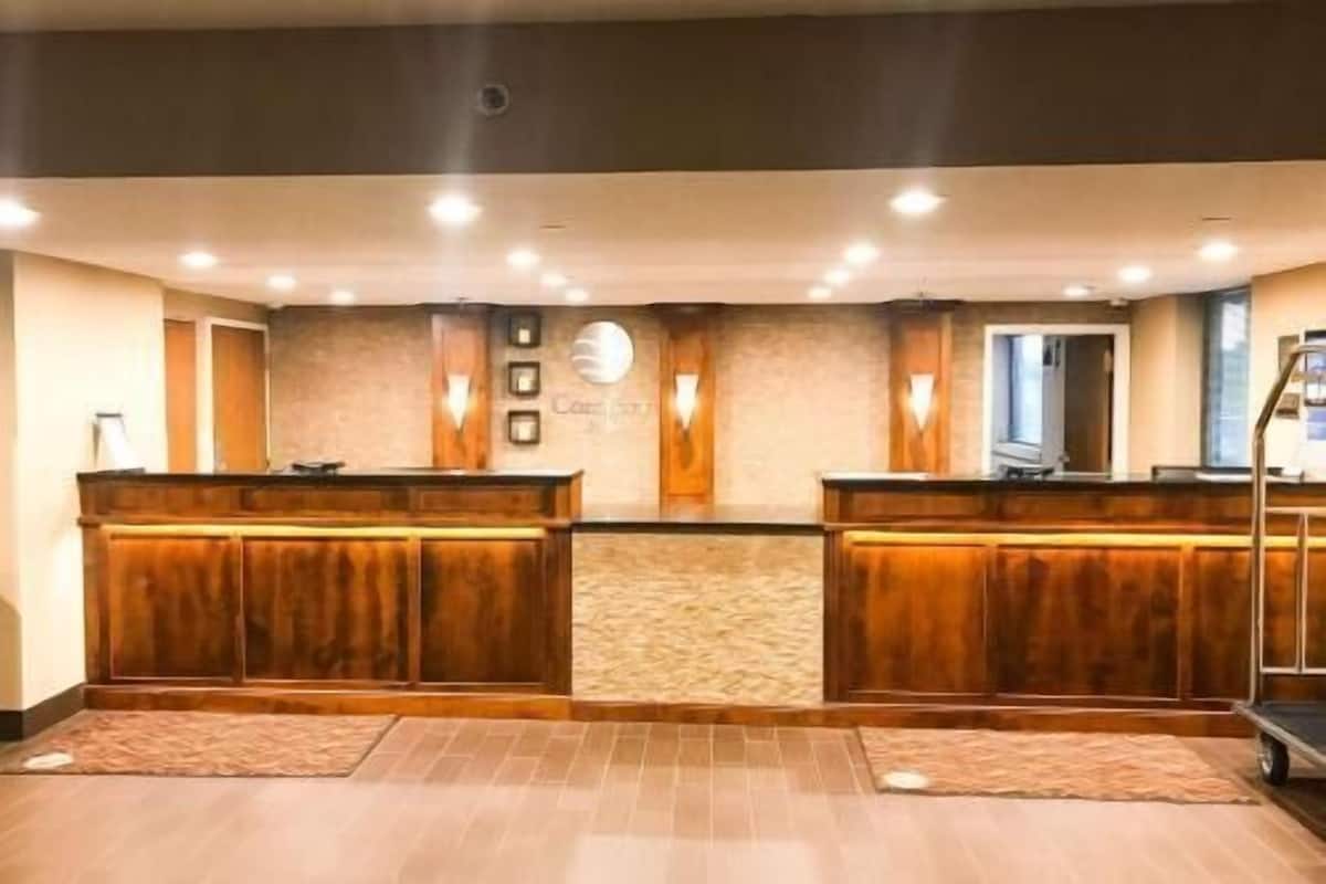 A reception area with a wooden reception desk, a clock, and a wall-mounted light fixture.