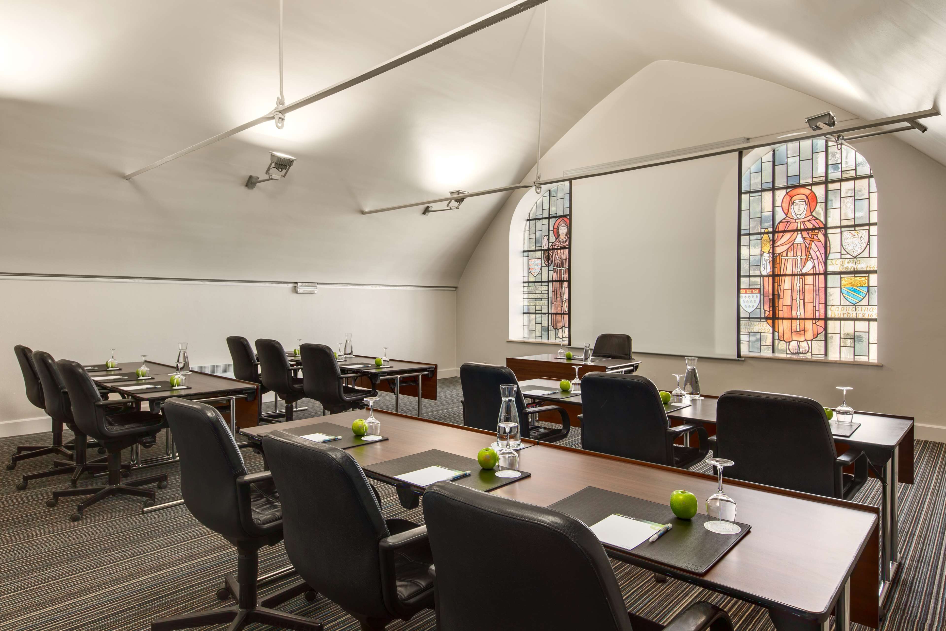 A conference room with a high ceiling, large windows with stained glass, and a modern interior design.
