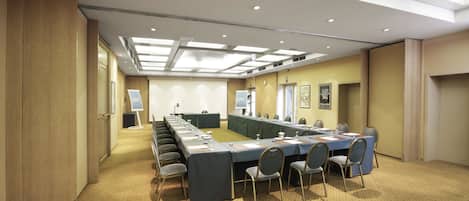 Un salón de conferencias con una larga mesa, sillas y piso alfombrado.