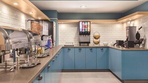 A modern kitchen with blue cabinets, stainless steel appliances, and a digital menu display. - Country Inn & Suites by Radisson Erie (Erie)