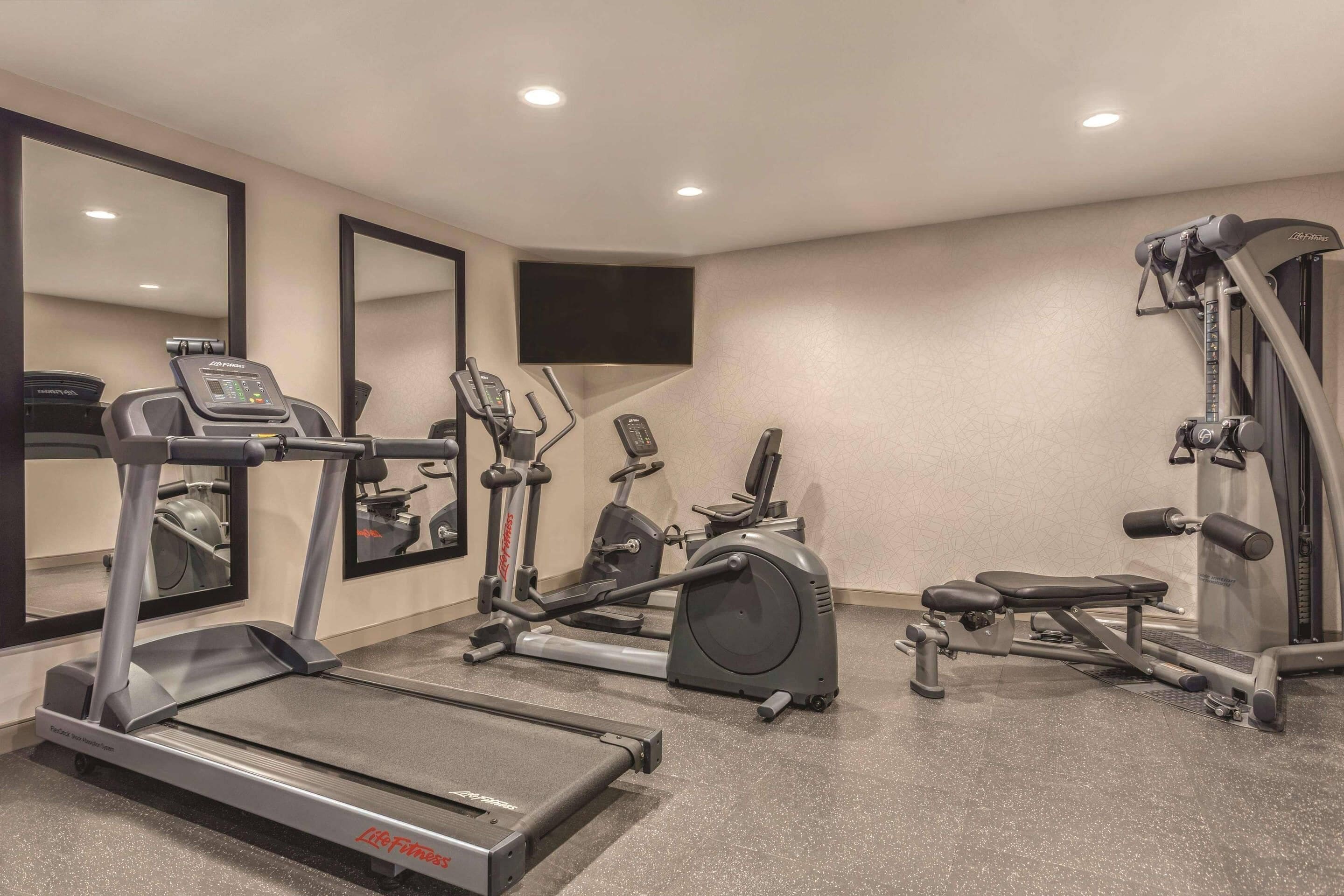 Une salle de sport équipée de tapis de course, de vélos elliptiques et d'appareils de musculation.
