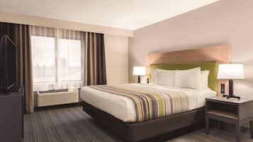 A hotel room with a large bed, two bedside tables with lamps, a flat-screen TV, and a large window with curtains.