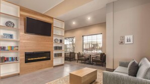 A modern living room with a fireplace, bookshelves, a flat-screen TV, and a sofa. - Country Inn & Suites by Radisson Erie (Erie)