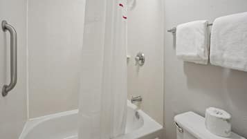A bathroom with a bathtub, a shower curtain, a toilet, and a towel rack.