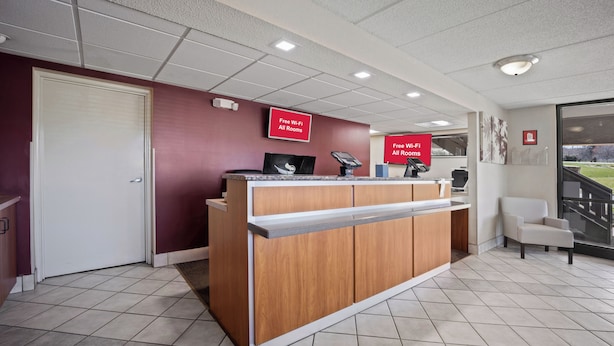 A reception desk with a digital screen, a cash register, and a sign indicating free Wi-Fi in all rooms. - Red Roof Inn Greensboro Airport (Greensboro)