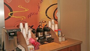 A coffee station with a coffee machine, cups, and various coffee-related items. - Red Roof Inn Greensboro Airport (Greensboro)