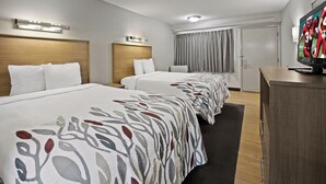 A hotel room with two beds, a desk, and a television. - Red Roof Inn Greensboro Airport (Greensboro)