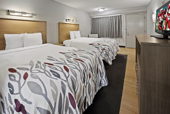 Una habitación de hotel con dos camas, un escritorio y una televisión.
