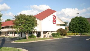 A Red Roof Inn with a red roof, white exterior, and a parking lot in front. - Red Roof Inn Greensboro Airport (Greensboro)