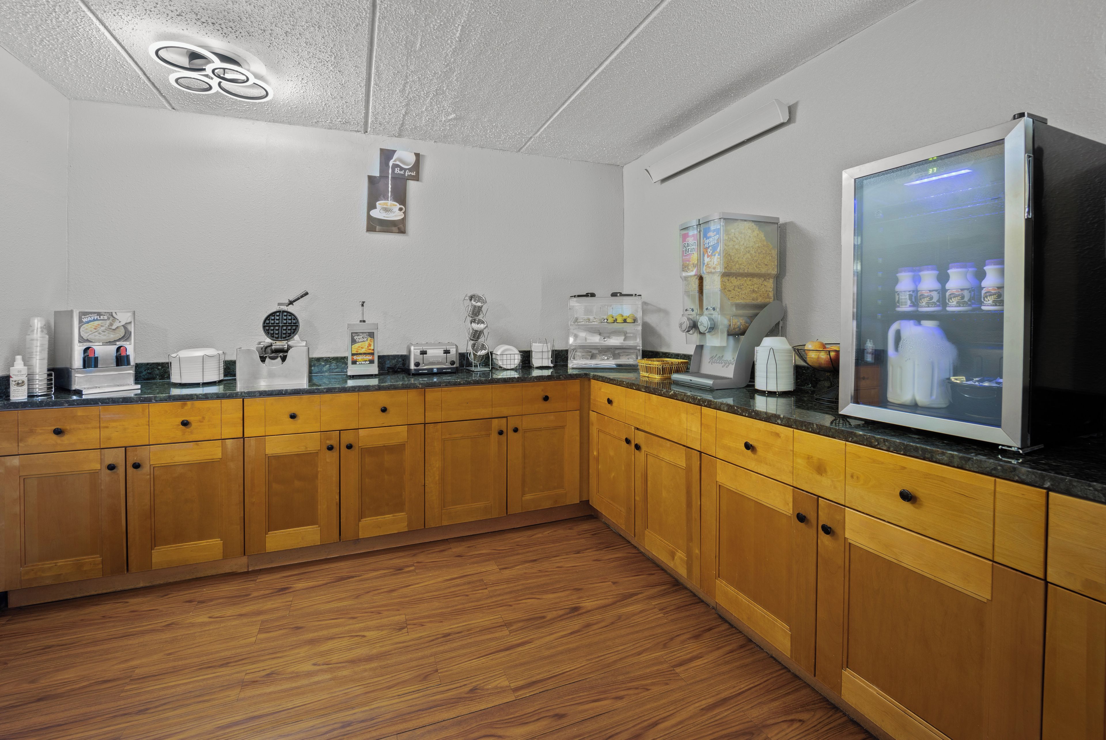 A kitchen with wooden cabinets, a coffee maker, a waffle maker, and a refrigerator.