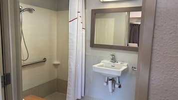 A bathroom with a shower, a sink, a mirror, and a towel rack.