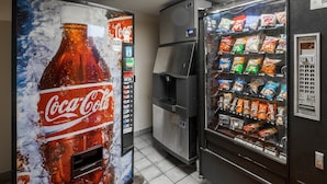 A vending machine with a Coca-Cola advertisement and a selection of snacks. - Red Roof Inn Greensboro Airport (Greensboro)
