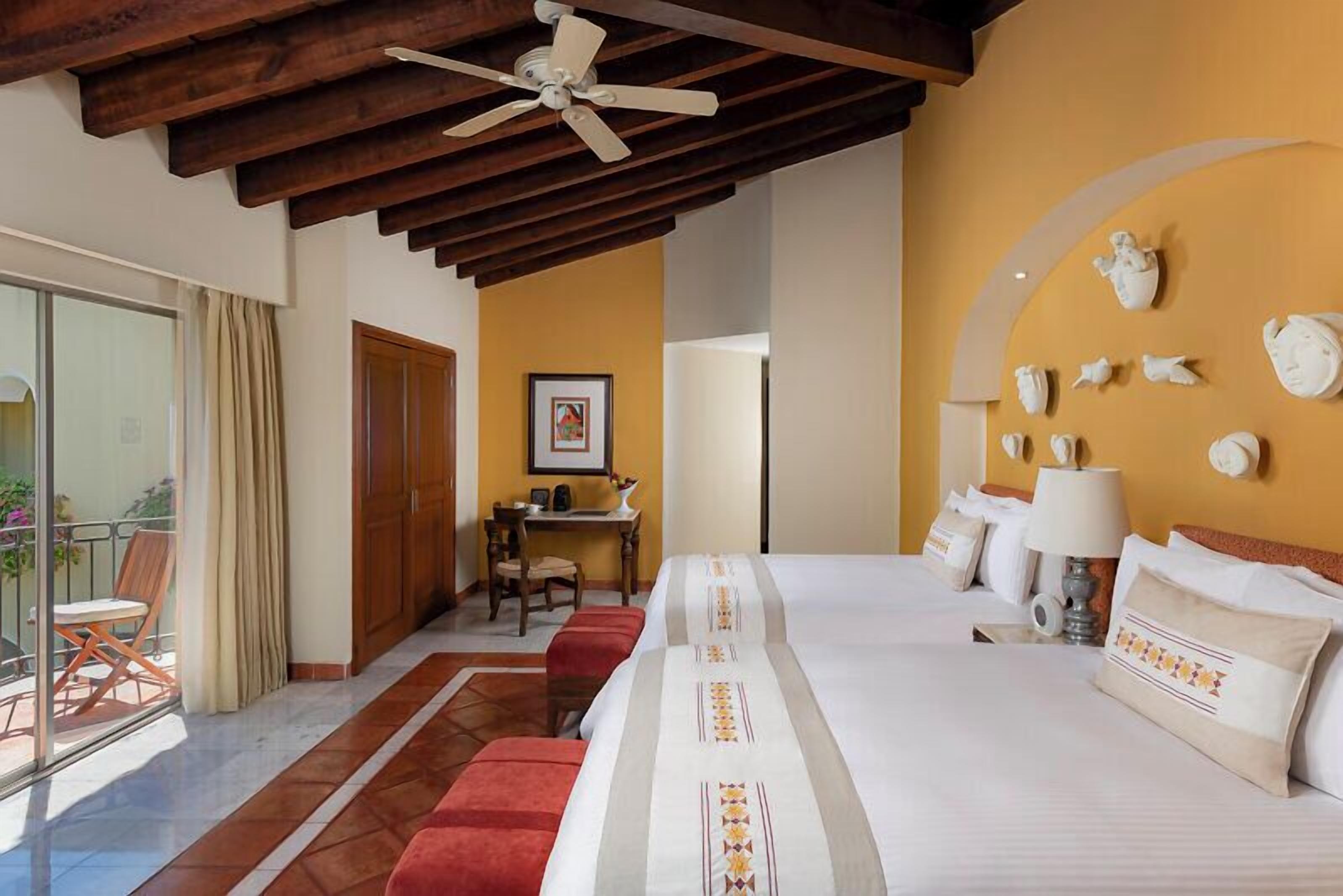 A hotel room with a large bed, a desk, and a balcony with a chair.