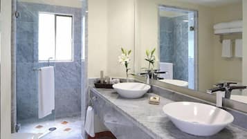 A modern bathroom with two large white sinks, a glass shower enclosure, and a large mirror.