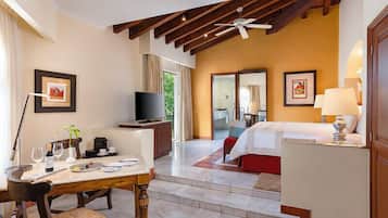 Una habitación de hotel con comedor, cama, televisor y ventilador de techo.