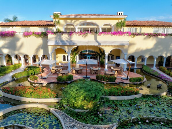 Un patio con piscina, zonas de estar y un edificio con arcos y columnas.