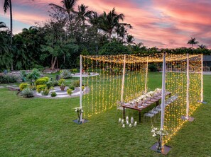 An outdoor wedding setup with a decorated table and string lights.