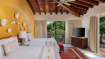 A hotel room with two beds, a TV, and a balcony with a view of greenery.