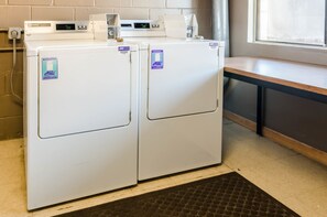 Convenient laundry facility with two front-loading washing machines and a comfortable seating area.