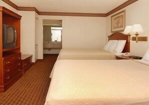 A hotel room with two beds, a wooden dresser, a television, and a nightstand with a lamp.