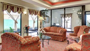A room with a patterned sofa set, a glass coffee table, and a ceiling fan.