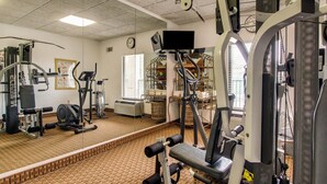 A gym with exercise equipment, a clock, and a window.